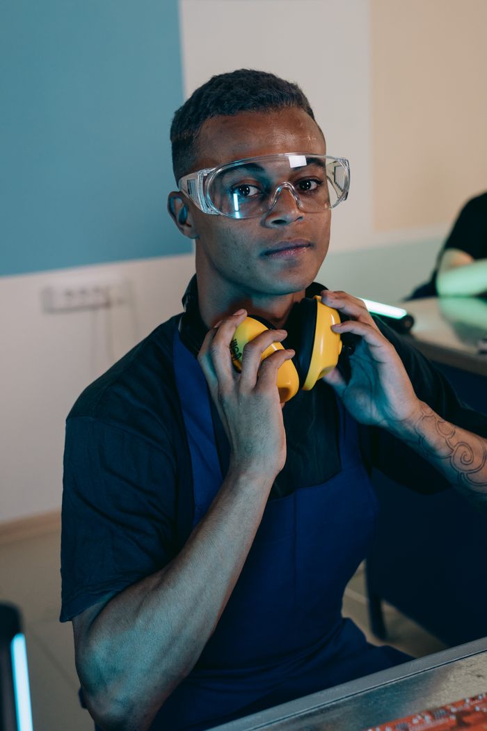 services-10 Portrait of a young engineer wearing safety glasses and headphones in a workspace.